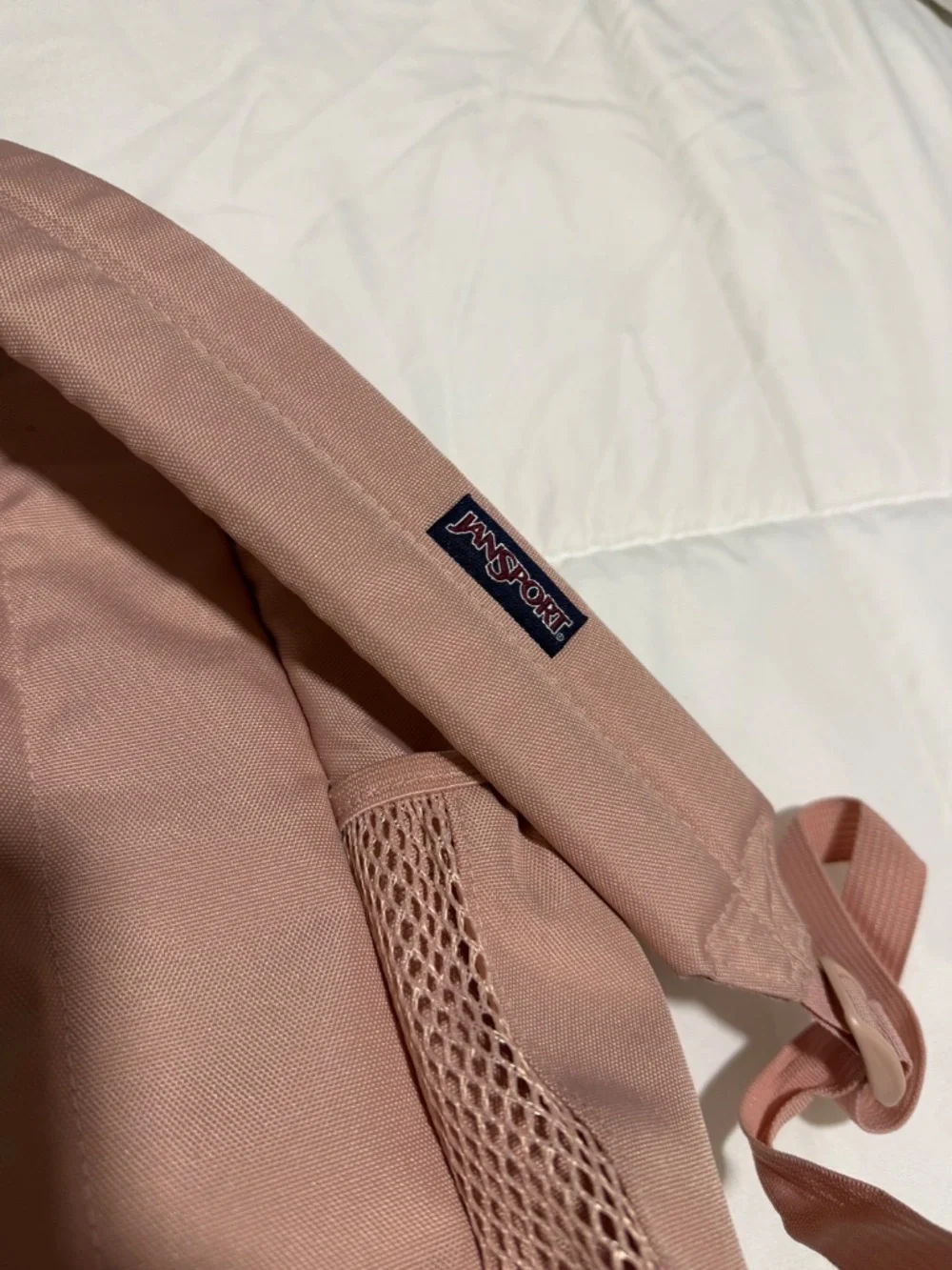 JanSport Cross Town backpack in a light pink color with a blue logo patch